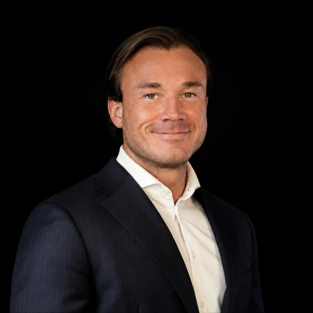 Portrait of Olav Henrik Trent wearing a dark suit and white shirt.